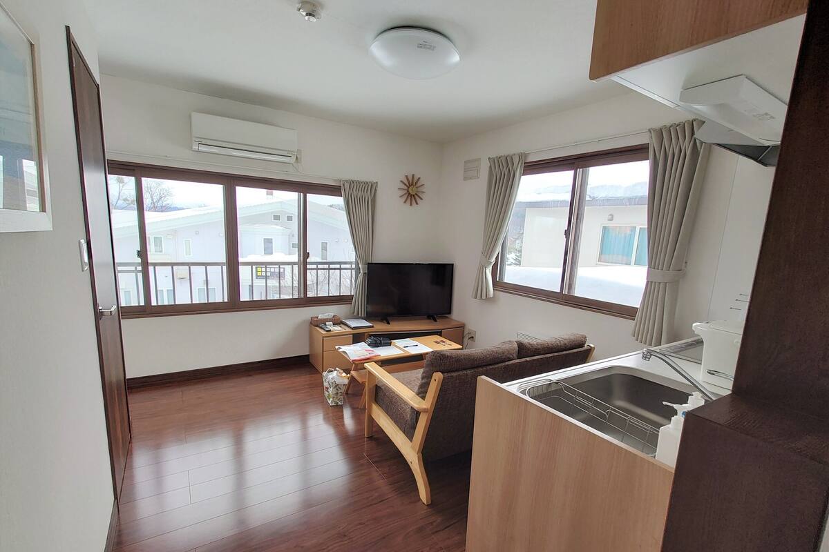 A compact living space with a kitchenette, a sofa, a TV, and a dining area.