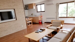 A modern living room with a sofa, a coffee table, and a TV mounted on the wall. - Kashiwa House Furano (Furano)