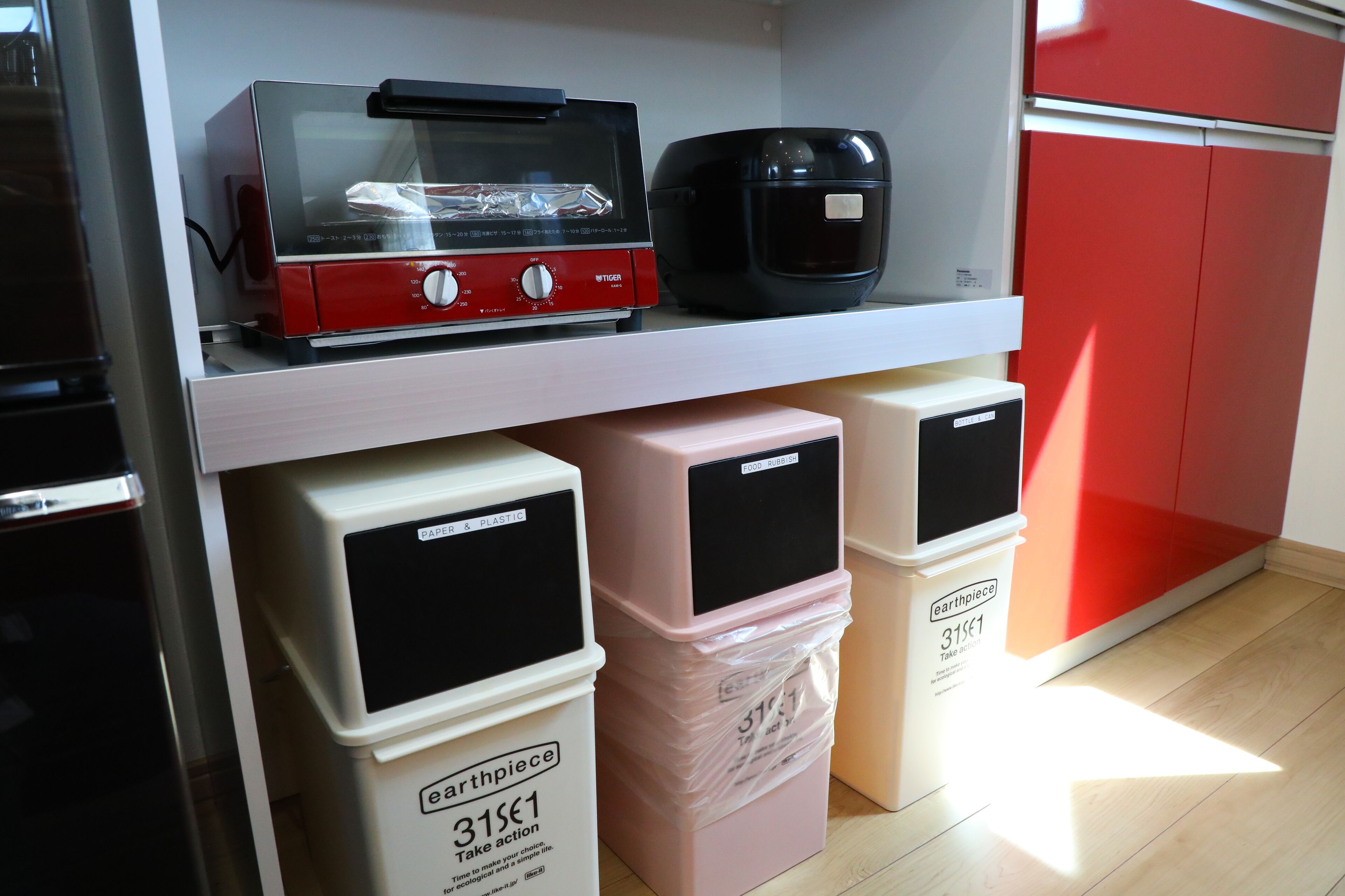 A kitchen area with a microwave, toaster, and plastic containers labeled "earthpiece" on a shelf.