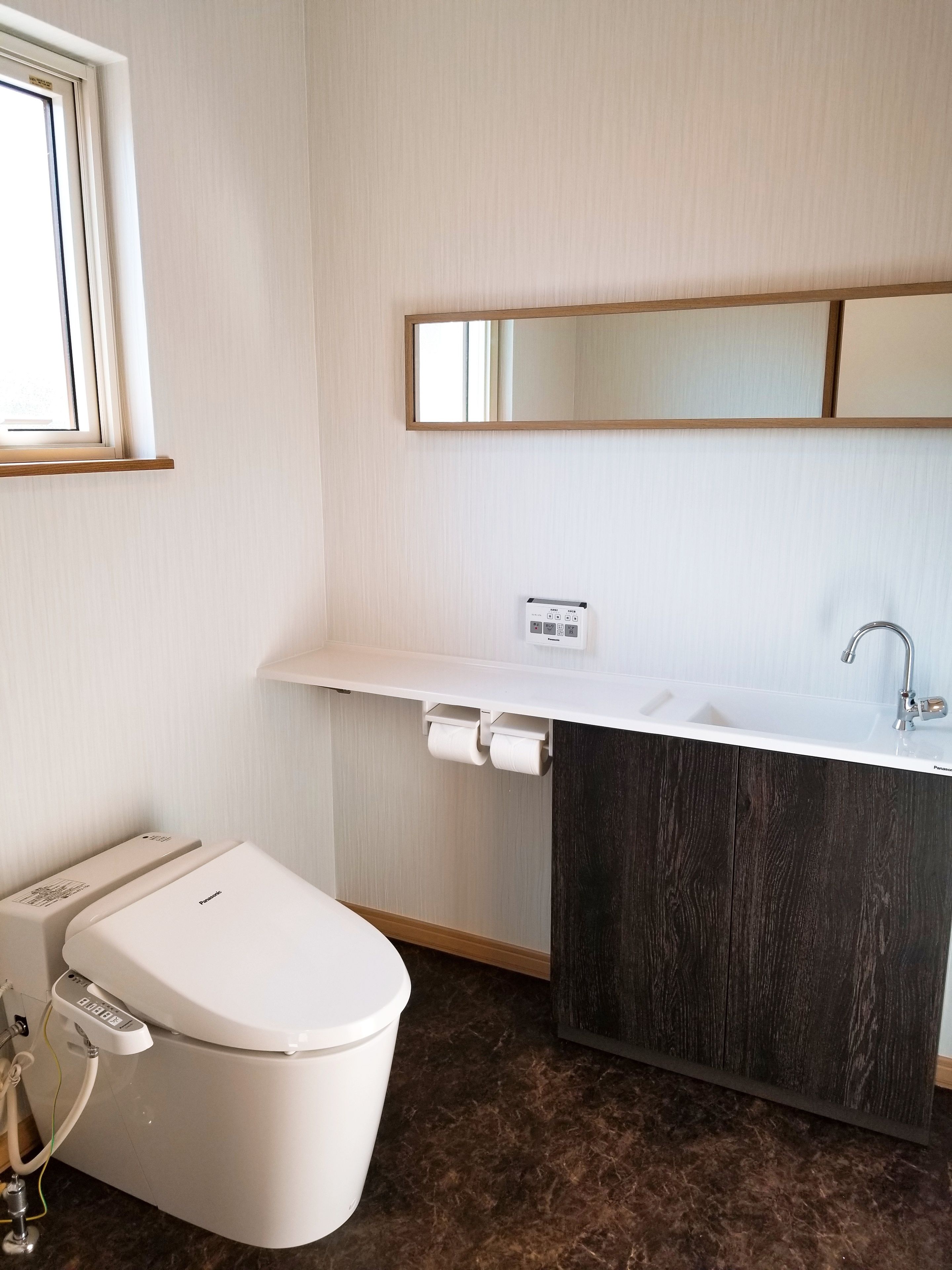 A modern bathroom with a toilet, sink, and mirror.