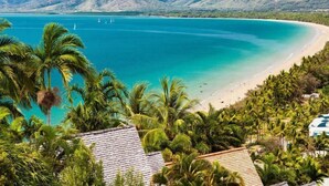 A coastal view with a beach, palm trees, and mountains in the background. - C215 Ramada Resort Deluxe King - Free Wifi (Port Douglas)