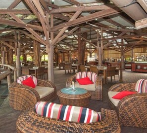 Un restaurant dont le mobilier est en osier et dont le plafond est constitué d’une structure en bois.