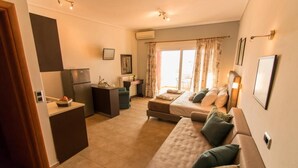 A compact living space with a kitchenette, a sofa set, a dining area, and a large window with curtains. - Evia Dream (Istiaia-Aidipsos)
