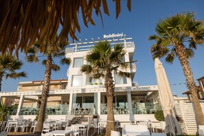 A hotel with a balcony, palm trees, and outdoor seating. - Baldinini Hotel (Rimini)