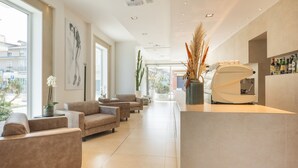 Um lobby moderno com balcão de recepção, área de estar e grandes janelas com vista para a cidade.