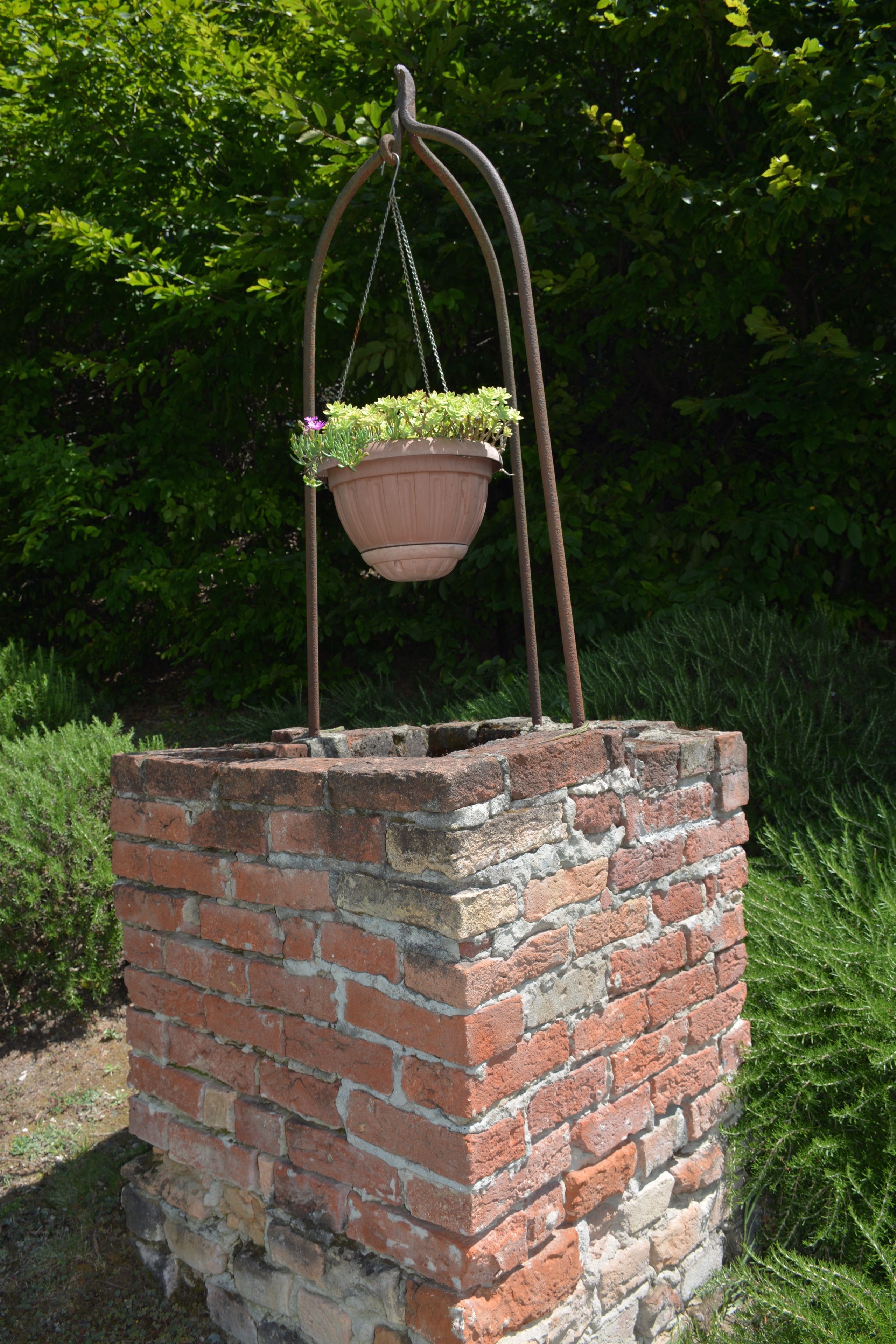 A hanging planter with plants on a brick structure.