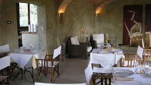 Een restaurant met bakstenen muren, witte tafellinnen en rieten meubels.
