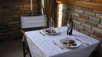 Mesa lista para dos personas, con platos de comida, copas de vino y cubiertos.