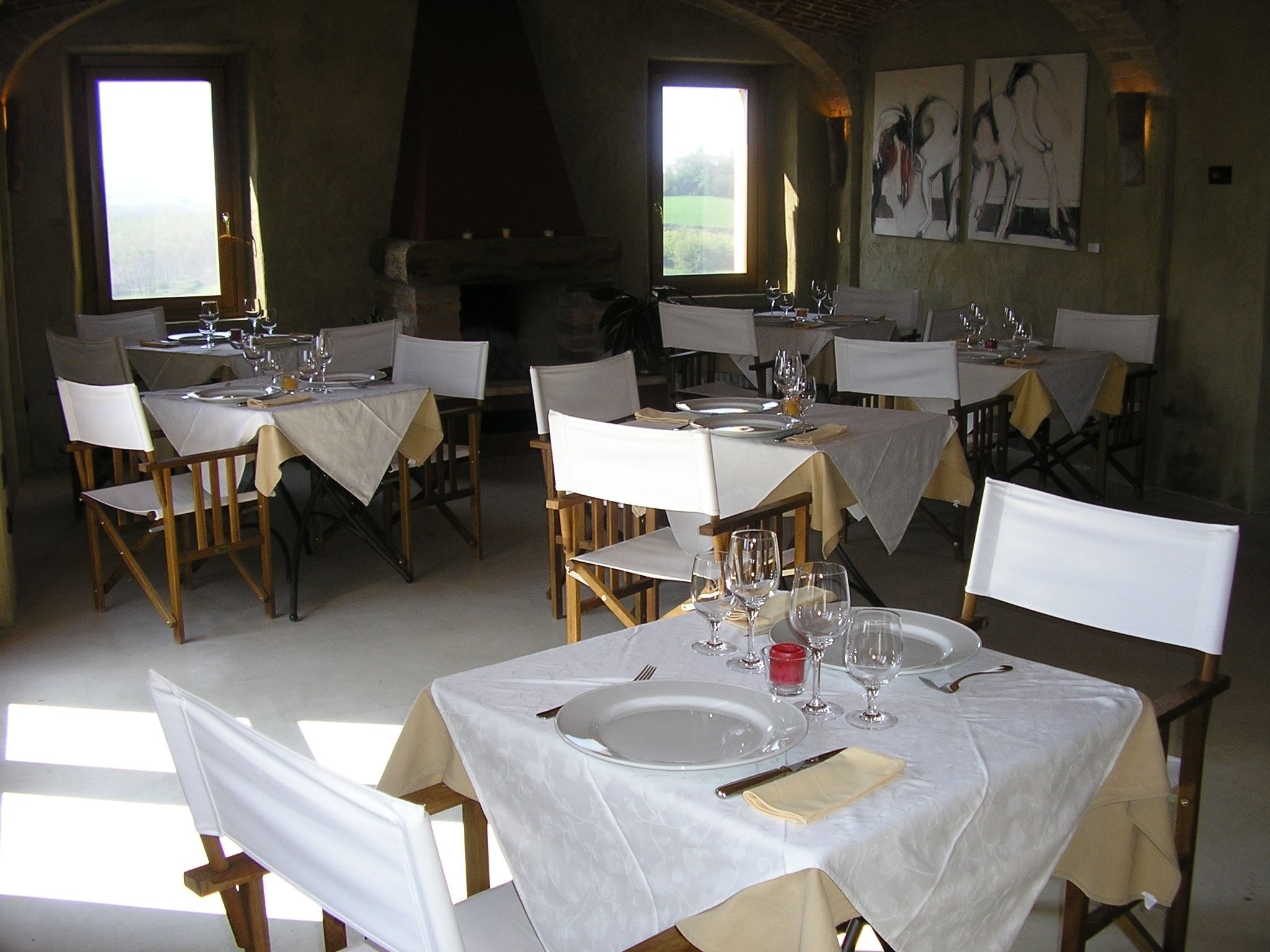 Un comedor con mesas dispuestas para dos, manteles blancos y sillas.