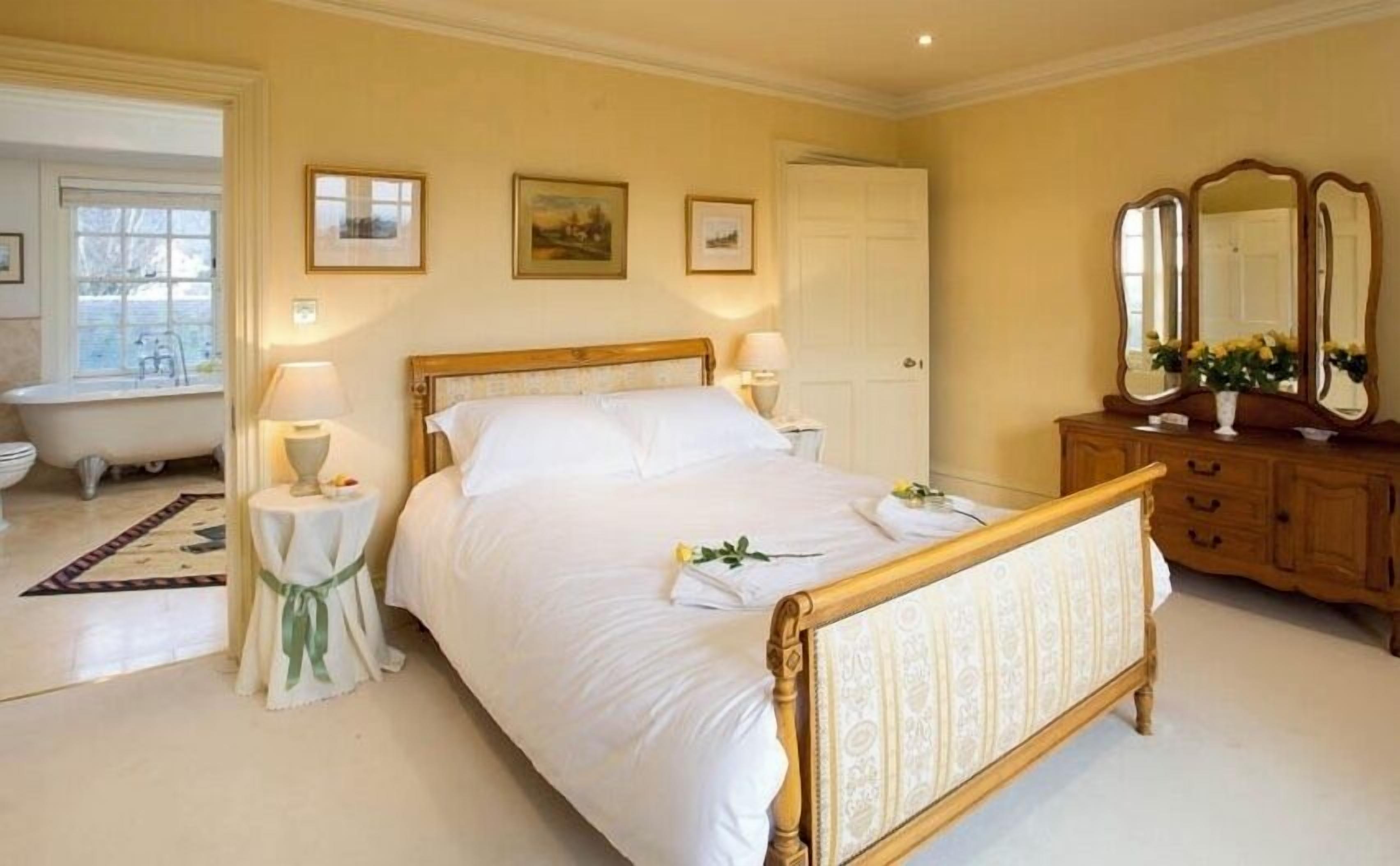 Une chambre à coucher avec un grand lit, des tables de chevet, une commode et un miroir.