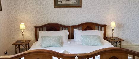 A neatly made bed with two pillows, a wooden headboard, and two bedside lamps.