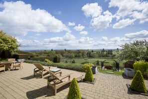 An outdoor patio with wicker furniture and a view of the countryside. - Bowden House B&B (Melrose)