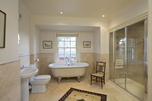 A bathroom with a freestanding bathtub, a toilet, a sink, and a glass-enclosed shower area. - Bowden House B&B (Melrose)