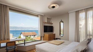 Un dormitorio moderno con un ventanal grande, una cama, un escritorio y un televisor.