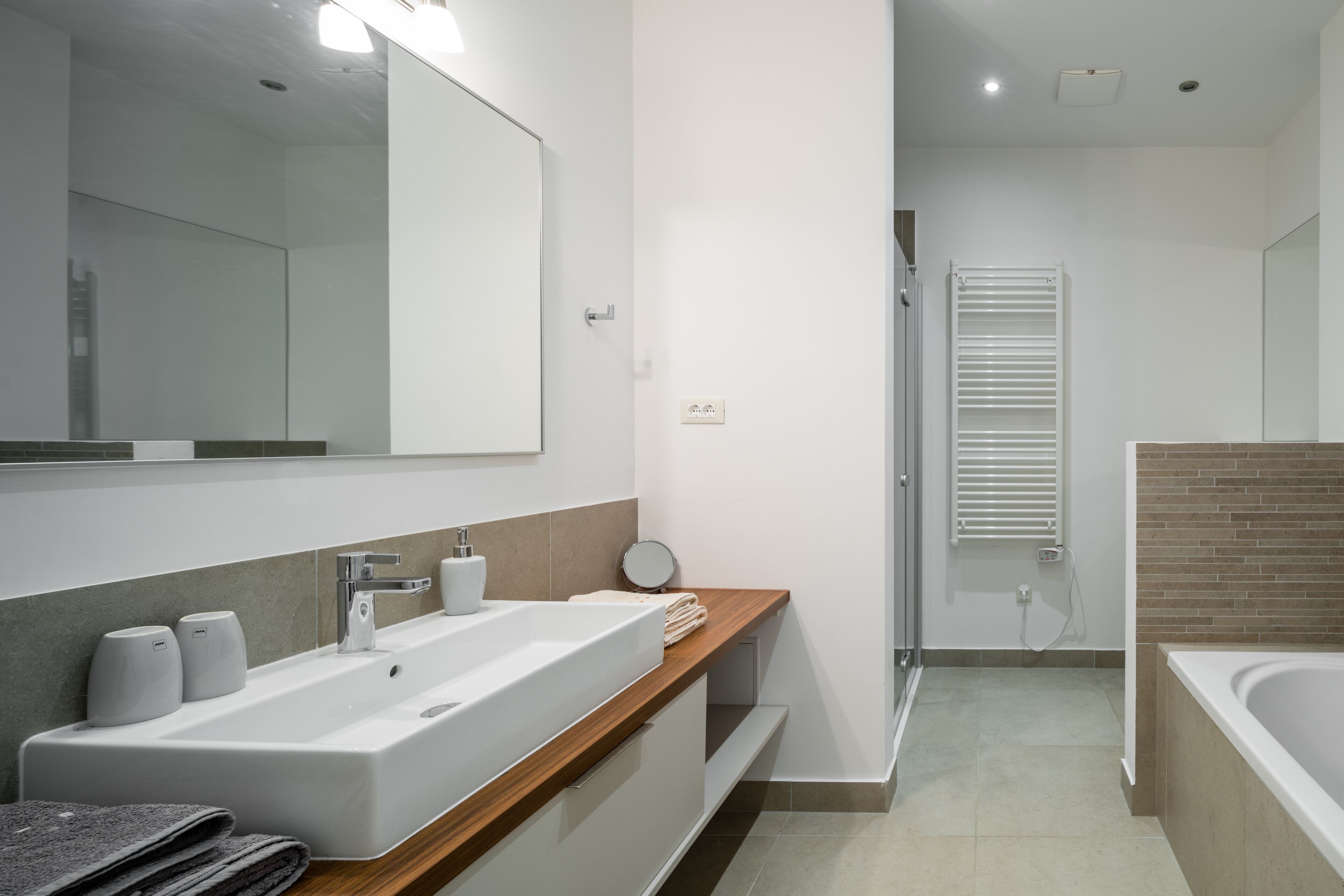 Un baño moderno con un lavamanos amplio, espejo y cabina de ducha.