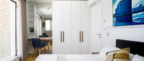A modern hotel room with a bed, a desk, and a wardrobe.