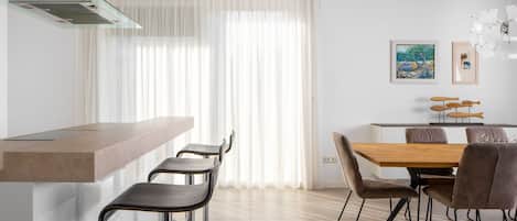 Une cuisine moderne avec un coin bar, une table à manger avec des chaises et des œuvres d’art accrochées au mur.
