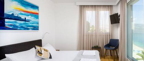Une chambre d’hôtel avec un grand lit, une chaise, une télévision et un tableau au mur.