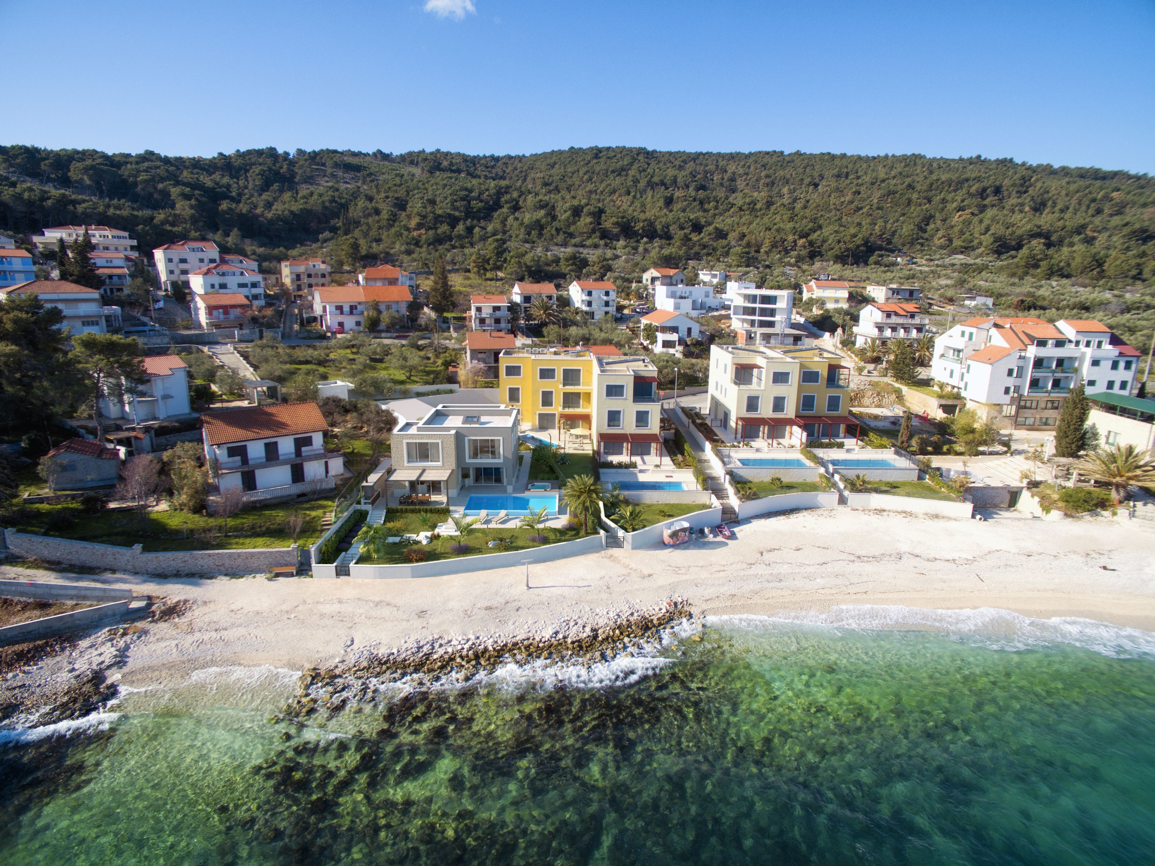 A coastal residential area with houses, a beach, and clear waters.