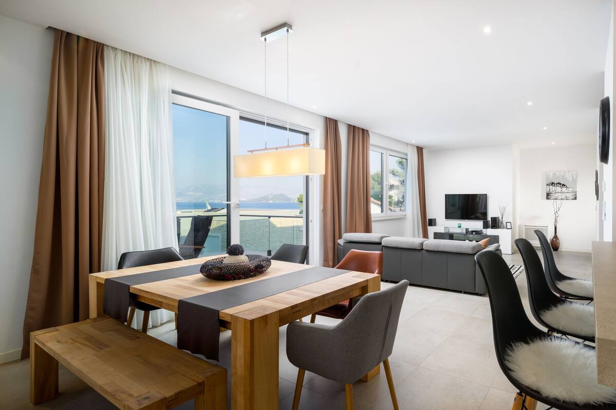 A modern hotel room with a dining area, a sofa, and a TV.
