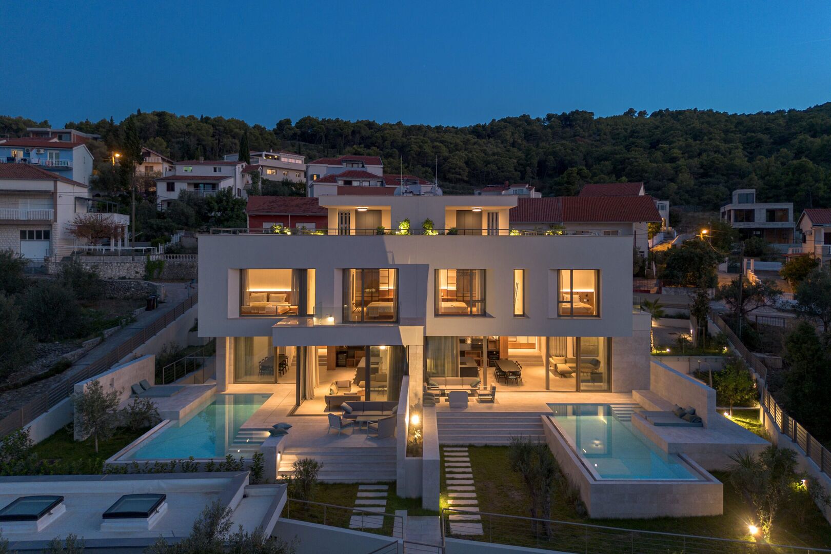 A modern two-story house with a swimming pool, multiple bedrooms, and a well-lit outdoor area.
