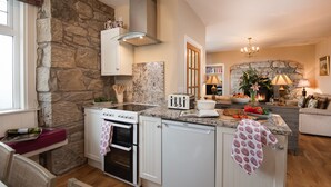 A kitchen with a stone wall, a built-in oven, a dishwasher, and a granite countertop. - Bartlehill Cottage, Idyllic Pet Friendly Cottage, Beautiful Scottish Borders (Coldstream)