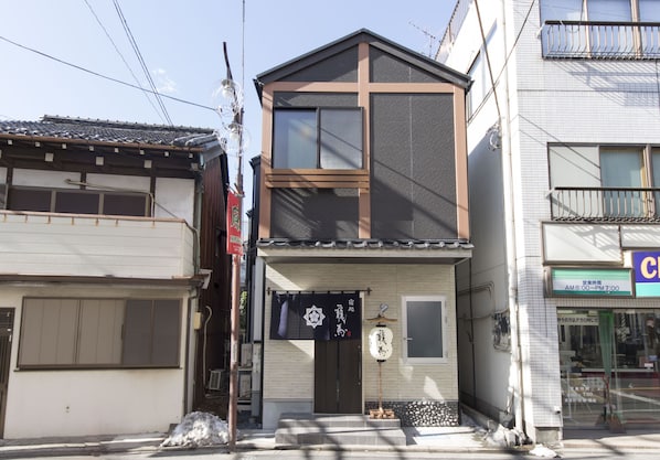 Ein traditionelles japanisches Gebäude mit zweistöckiger Struktur, einer Schiebetür und einer kleinen Veranda.