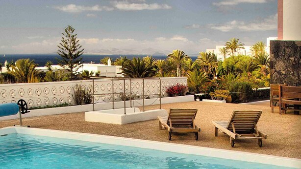 A rooftop pool area with lounge chairs, a view of the ocean, and tropical landscaping. - CASA JUANITA by Buenavilla | Exclusive apartment with private pool (Puerto Calero)