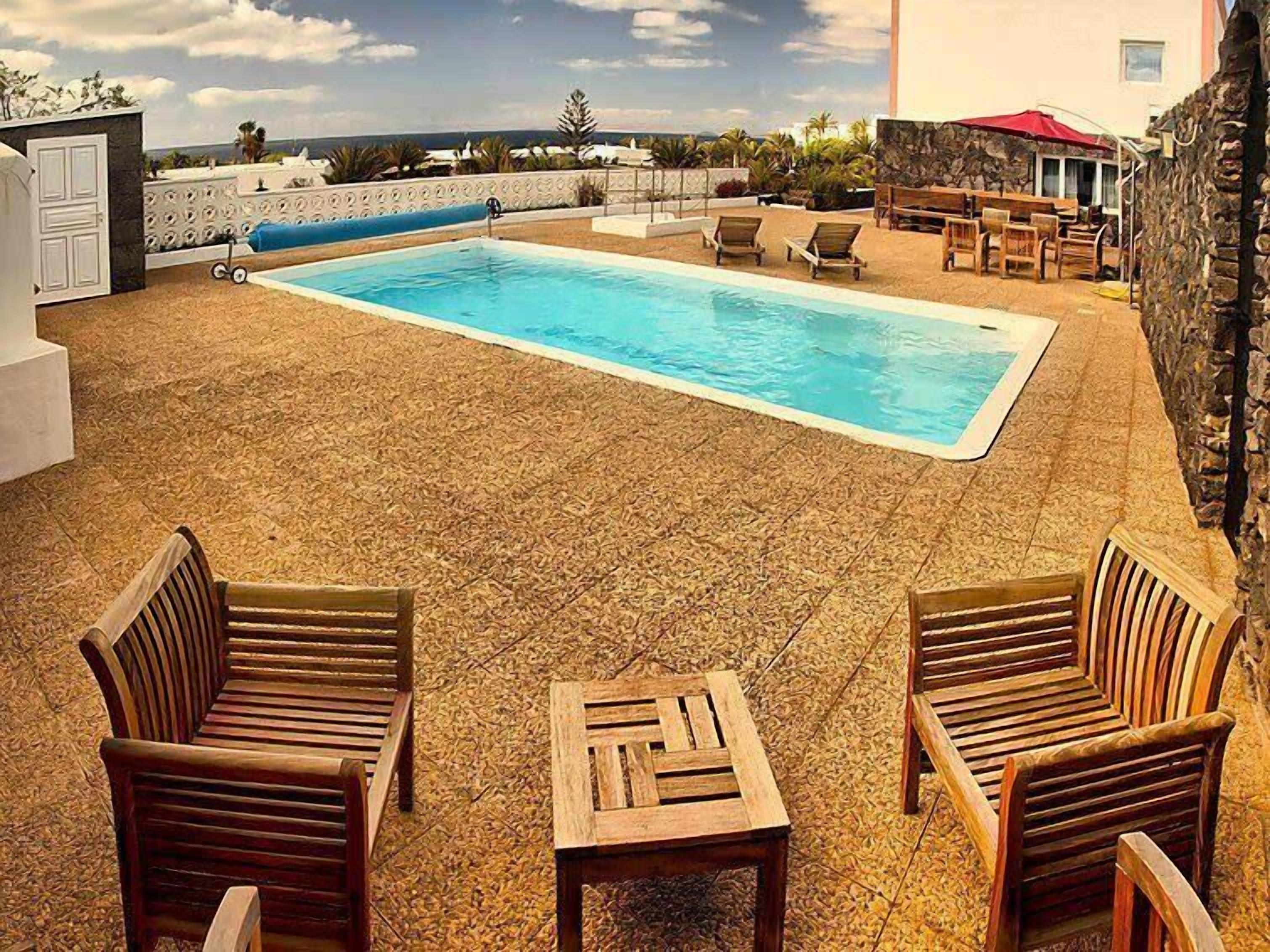 A pool area with a stone wall, lounge chairs, and a table.