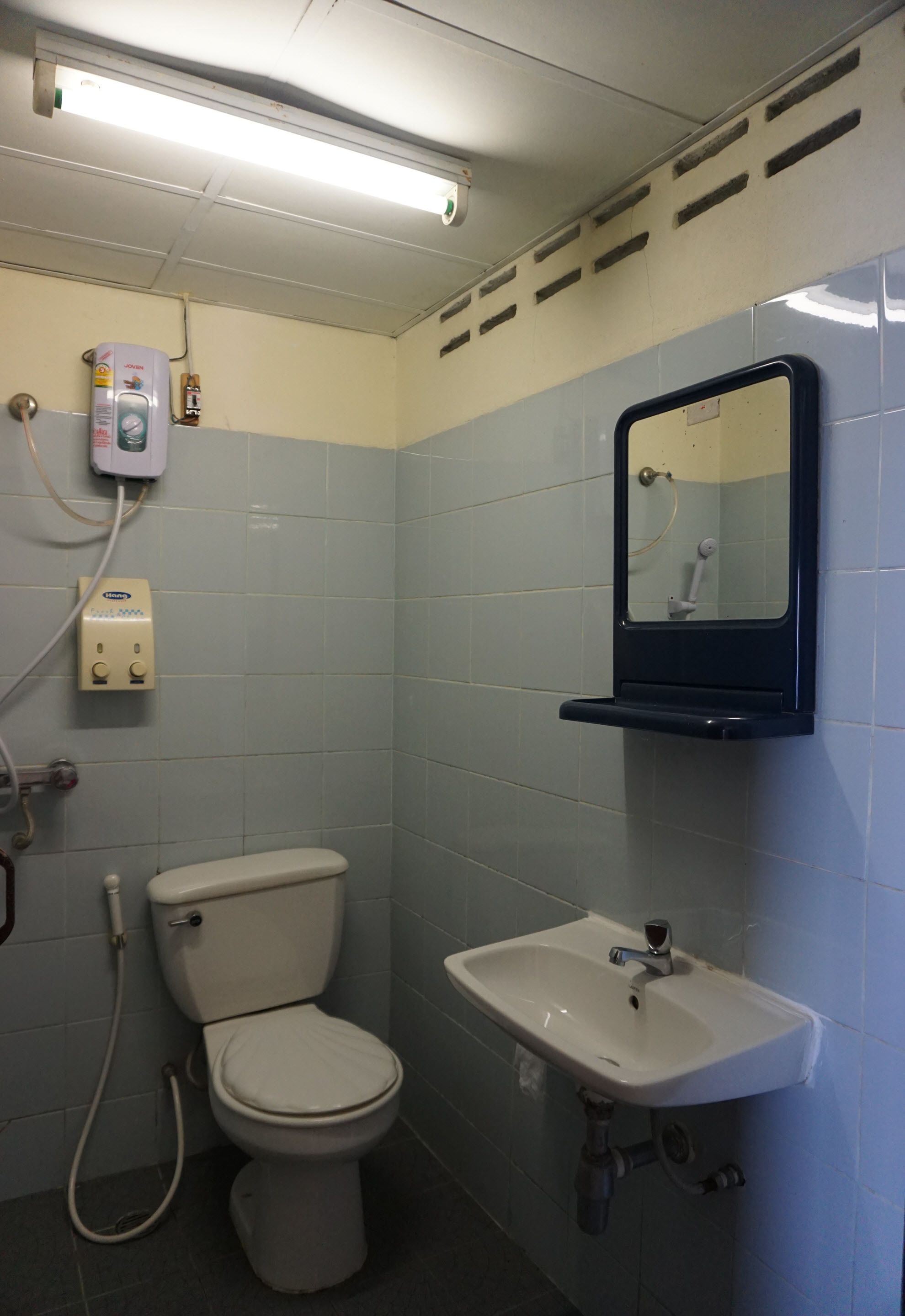 Un baño pequeño con inodoro, lavamanos y espejo.