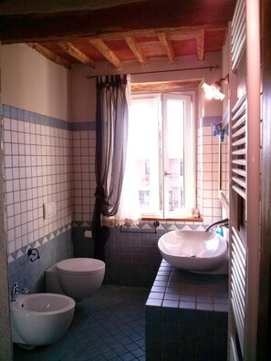 A bathroom with two sinks, a toilet, and a window with curtains. - La Coccinella (Massarosa)