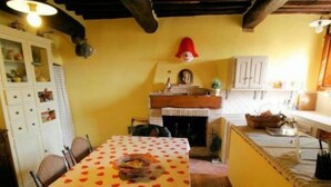 A dining area with a table covered in a polka dot tablecloth, a fireplace, and a red hat on the wall. - La Coccinella (Massarosa)