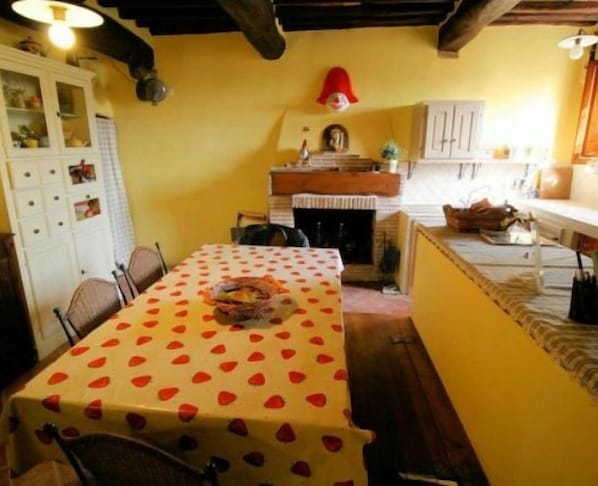 A dining area with a table covered in a polka dot tablecloth, a fireplace, and a red hat on the wall.
