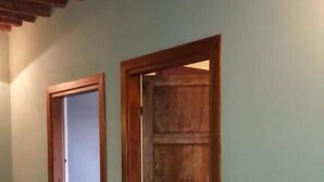 A hallway with wooden doors and a sloped ceiling. - La Coccinella (Massarosa)