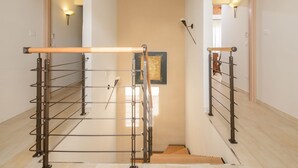 A staircase with metal railings and wooden handrails, leading to a landing with a framed artwork.