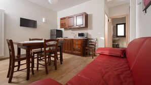 A compact living space with a dining area, kitchenette, and a red sofa.