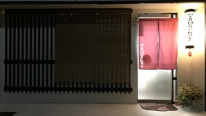 L’entrée d’un hôtel, avec une porte coulissante, un petit paillasson et une plante en pot.