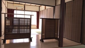 Une pièce de style japonais traditionnel, avec un sol recouvert de tatamis, des portes coulissantes et un lit bas en bois.