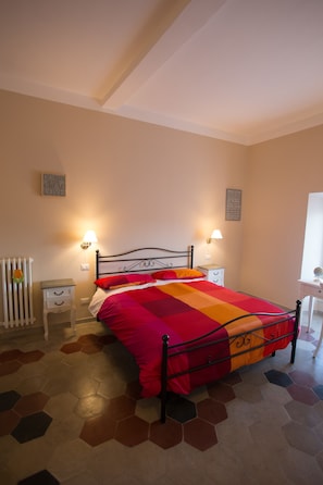 A bedroom with a bed, bedside tables, a radiator, and a window. - Alloggio Quiriti (Rome)
