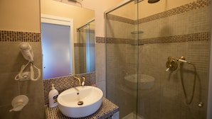 A bathroom with a white sink, a mirror, a glass shower enclosure, and a towel rack. - Alloggio Quiriti (Rome)