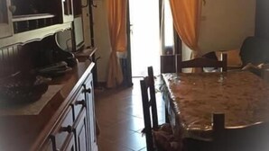 Een keuken met kasten, een eettafel, stoelen en een hanglamp.