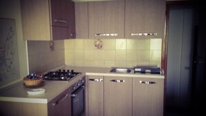 Een keuken met houten kastjes, een gasfornuis en een betegelde spatwand.