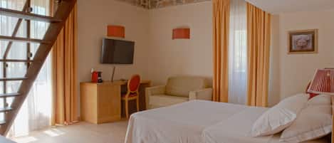 Quarto com uma cama, uma escrivaninha, uma cadeira, uma televisão e um telefone.