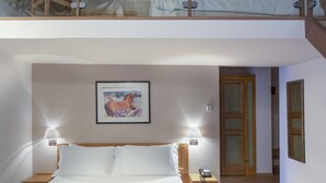 A bedroom with a large bed, a nightstand, a lamp, a framed picture on the wall, and a balcony with a chair. - Hotel 99 Cannelle (L'Aquila)