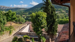 A view of a mountainous landscape with a stone wall and a tiled roof structure. - Hotel 99 Cannelle (L'Aquila)