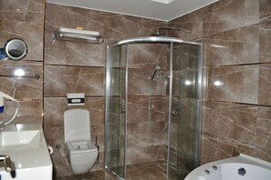 A bathroom with a glass-enclosed shower, a toilet, a sink, and a bathtub. - Olea Hotel (Kilis)