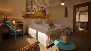 A bedroom with a bed, a desk, a chair, and a painting on the wall.