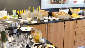 A buffet setup with various food items, drinks, and utensils.