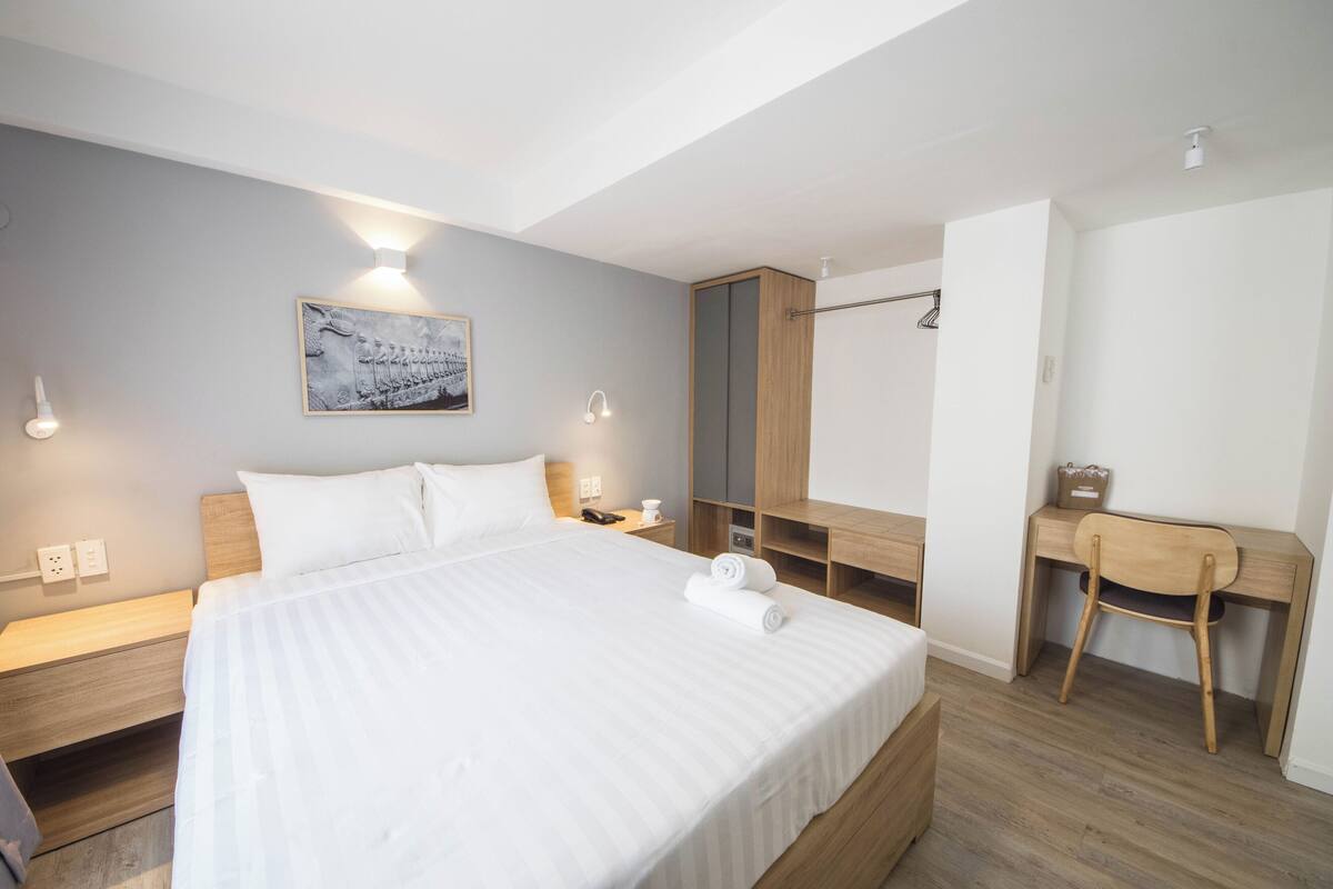 A modern hotel room with a large bed, bedside tables, a desk, and a chair.