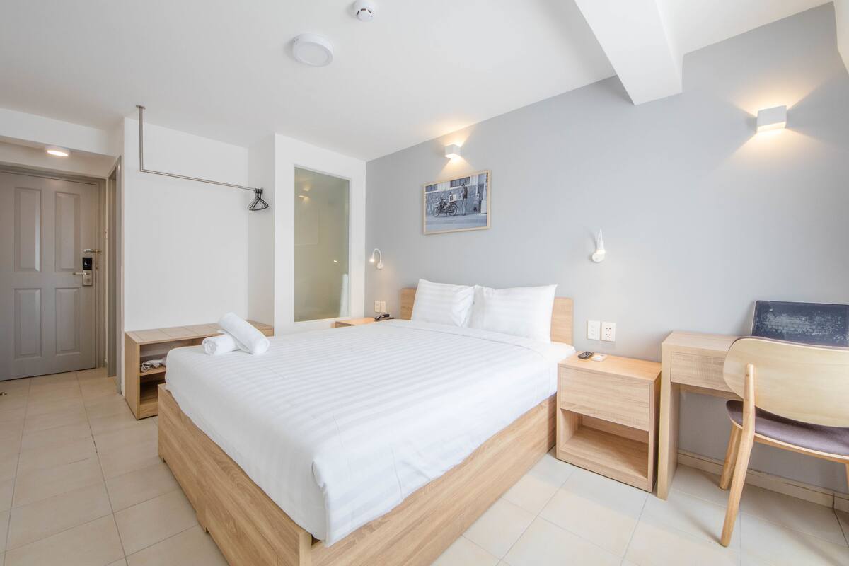 A modern bedroom with a large bed, bedside tables, a desk, and a chair.